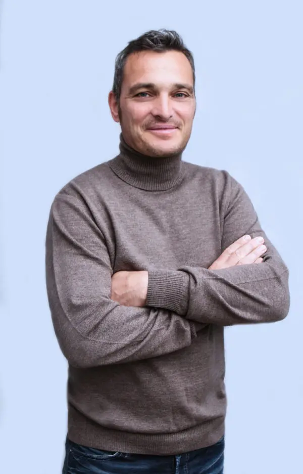 Ein Mann trägt einen nougatfarbenen Merinopullover mit Rollkragen.