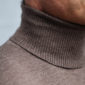 Detailaufnahme vom Halsbereich eines Mannes. Er trägt einen nougatfarbenen Rollkragenpullover