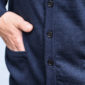 Eine Detailaufnahme einer Hand in der Tasche eines dunkelblauen Cardigans mit Knöpfen.