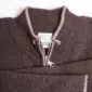 Eine Nahaufnahme von dem Kragen einer braunen Merinostrickjacke. Auf dem eingenähten Etikett ist das my pulli Logo zu sehen.