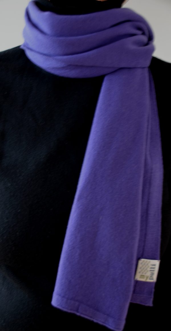 Ein violetter Kaschmirschal locker um den Hals geschlagen.