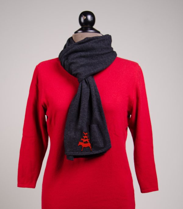 Eine Kleiderpuppe trägt einen roten Pullover. Um den Hals in Schlaufe geschlagen ist ein anthrazirfarbener Schal mit aufgestickten Bremer Stadtmusikanten in rot.
